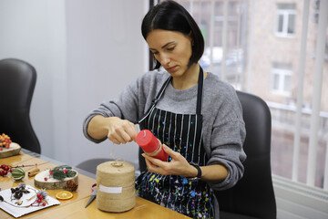 Brunette woman winding rope around a candle. Woman creates christmas decorations, new year gifts. Craftwork, handcraft, handwork