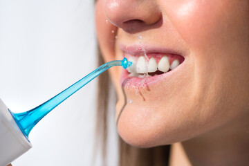 Closeup of woman with perfect smile using water flosser or oral irrigator