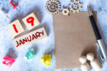 Wooden calendar 19 January with frame for photo on white table and background close-up