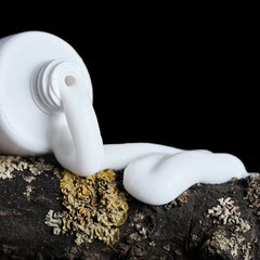 Close-up of a fragment of an open tube with white cream on a dark background. Minimalistic concept of fighting skin fungal diseases. Selective focus