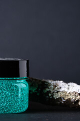 Close-up of a jar of cosmetics on an abstract dark background. Turquoise gel. Selective focus. copy space