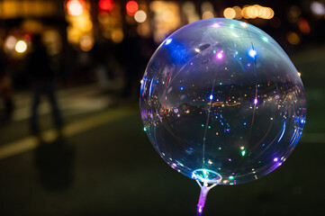 Photo of balloon and colorful holiday lights showing in the background outdoors at night. - obrazy, fototapety, plakaty