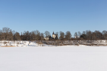 Landscape view from river shore with old 19th century manor and wooden buildings