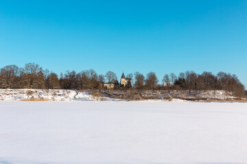 Fototapeta na wymiar Landscape view from river shore with old 19th century manor and wooden buildings