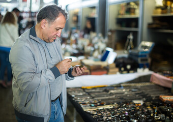 Positive middle aged man buying retro handicrafts on indoor flea market