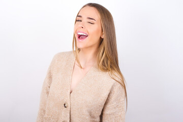 young caucasian girl wearing knitted sweater over white background winking looking at the camera...