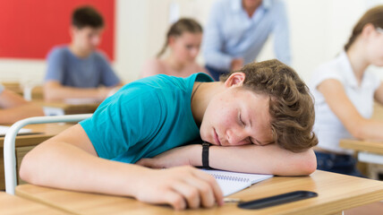 Tired student fell asleep on desk in the class