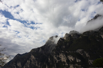 Low angle shot of rugged mountain peaks with white puffy clouds.