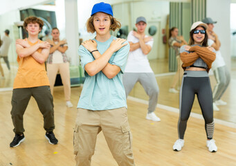 Emotional teen b-boy dancing with group of friends in dance studio. Hip-hop generation.