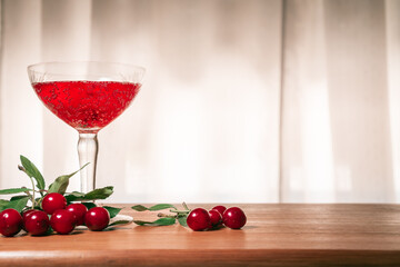 Flavored red fruit cider accompanied by cherries, on a wooden surface