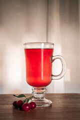 Flavored red fruit cider accompanied by cherries, on a wooden surface
