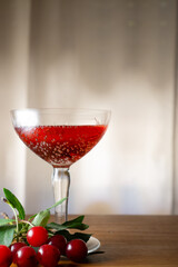Flavored red fruit cider accompanied by cherries, on a wooden surface