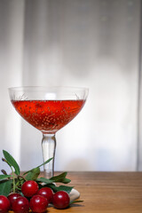 Flavored red fruit cider accompanied by cherries, on a wooden surface