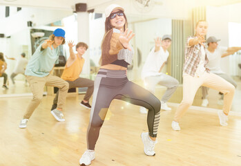 Fototapeta na wymiar Teens training hip-hop dance moves during group rehearsal in studio.