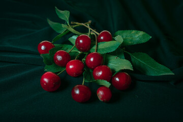 Cherries with some leaves on an elegant black cloth