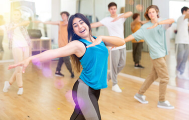 Group of active teens rehearsing modern dance in studio.