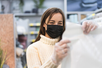 Young woman wearing protective face mask and protective gloves in store. Today people lifestyle concept. Virus protection. Health, safety and pandemic concept.