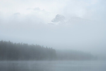 A mysterious morning at Two Jack Lake in Banff as fog shrouds most of the scene with just a peak poking out above the mist.