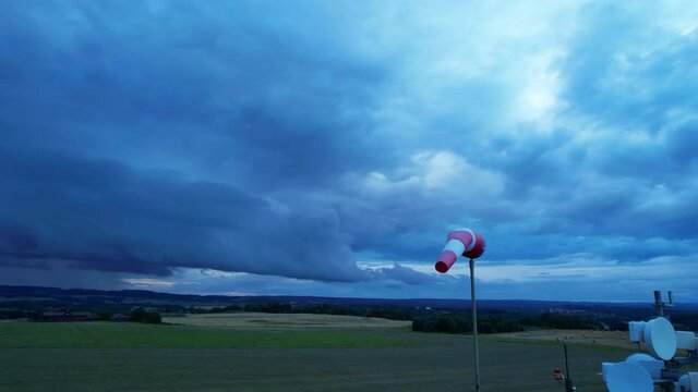 The wind pointer flutters in the wind, showing the direction and speed of the wind on a dark blue storm clouds.