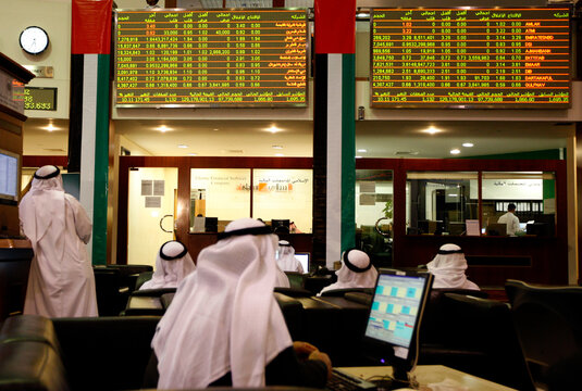Investors look at stock exchange information at the Dubai