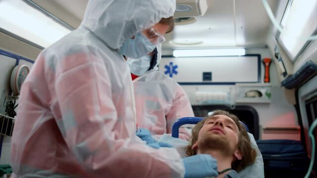 Emergency medical doctors giving first aid help to patient in ambulance car