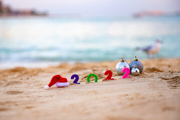 Santa Claus hat 2022 numbers lie on the sand next to gifts