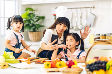 Portrait of enjoy happy love asian family mother and little asian girl daughter child having fun help cooking food healthy eat together with fresh vegetable salad and sandwich ingredient in kitchen