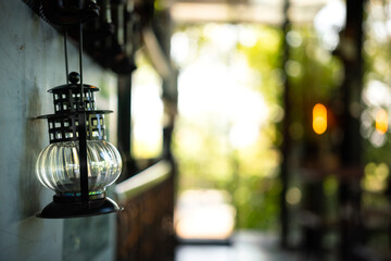 An ancient kerosene lantern lamp which is hanging on the wall for interior decoration, photo with blurred background of lighting bokeh. Close-up and selective focus at the object.