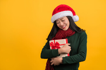 Portrait of a satisfied young girl holding present box isolated over yellow background