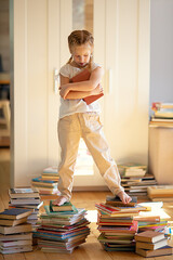 cute little girl is reading book and standing on pile of books. Children and education