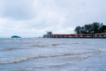 Horizontal shot of hotels built on water, water on foreground and sky on background at Port Dickson beach during heavy rain and wind. 