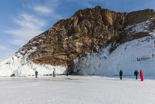 Winter Baikal Lake. Tourists travel on the ice of the frozen lake and take pictures of the beautiful icy rocks of Olkhon Island