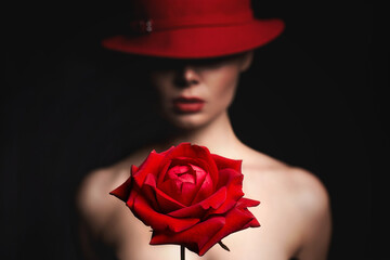 silhouette of beautiful woman in hat behind a red rose