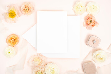 Romantic white blank wedding stationery card on an envelope arranged with fresh ranunculus flowers...