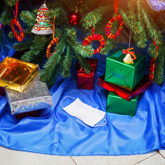 White protective medical mask among Christmas and New Year gifts in beautiful boxes under the Christmas tree