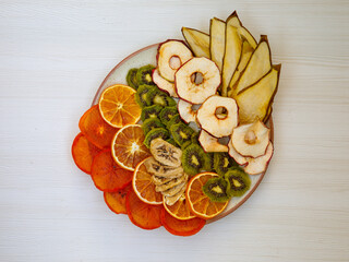 Healthy homemade fruit chips from apple, orange, banana, pear, watermelon, kiwi on white background. Organic vegan diet food. Dried fruits. Vegetarian plant based snack concept. Top view flat lay