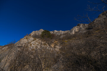 Views from former train track between Trieste and Kozina, above valley of Glinscica or Rosandra on a sunny winter day.  View of cliffs above path.