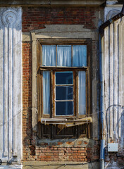 Fragment of the facade of an old brick house with a window and a drainpipe. The picture was taken in Russia, in the city of Orenburg