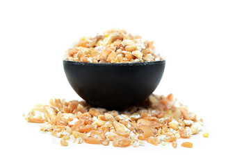 Flaked grains in measuring spoon, close up. Macro of flaked and not soaked mixed cereal grains, made with a grain flaker. Hard wheat kernels, sorghum, millets and pearled barley. Selective focus.