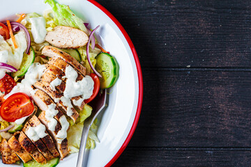 Buffalo chicken salad with gorgonzola cheese, tomato, cucumber and ranch dressing, dark wooden...