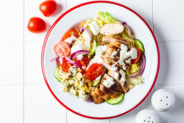 Buffalo chicken salad with blue cheese, tomato, cucumber and ranch dressing, white tile background. - obrazy, fototapety, plakaty