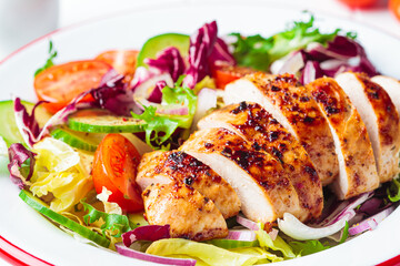 Chicken breast salad with cucumber, tomato and onion in a white plate, white background.
