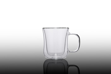 Double glass cup on a white background. Double glass cup isolated. Contemporary glass cup. Empty glass coffee cup on the mirror.