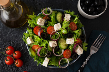 Greek salad with tomatoes, cucumbers, olives and feta cheese in a plate on a concrete background
