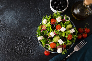 Greek salad with tomatoes, cucumbers, olives and feta cheese in a plate on a concrete background, typical Greek cuisine
