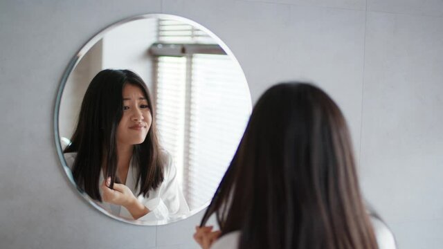 Asian Woman Touching Hair Having Split Ends Problem In Bathroom