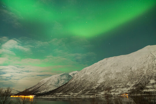 Breathtaking Aurora Borealis over mountain and lake water in Kvaloya, Arctic region in Norway