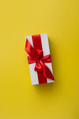 Gift box with a red bow on a yellow background, minimalism. Christmas, Valentine's Day, Birthday