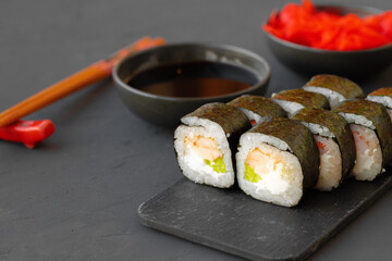 Maki sushi roll served on stone plate on gray background