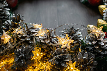Christmas composition on a wooden background, Christmas cones and balls, green sprigs of needles, yellow lanterns in the form of stars and space for text, beautiful decoration for the home and design
